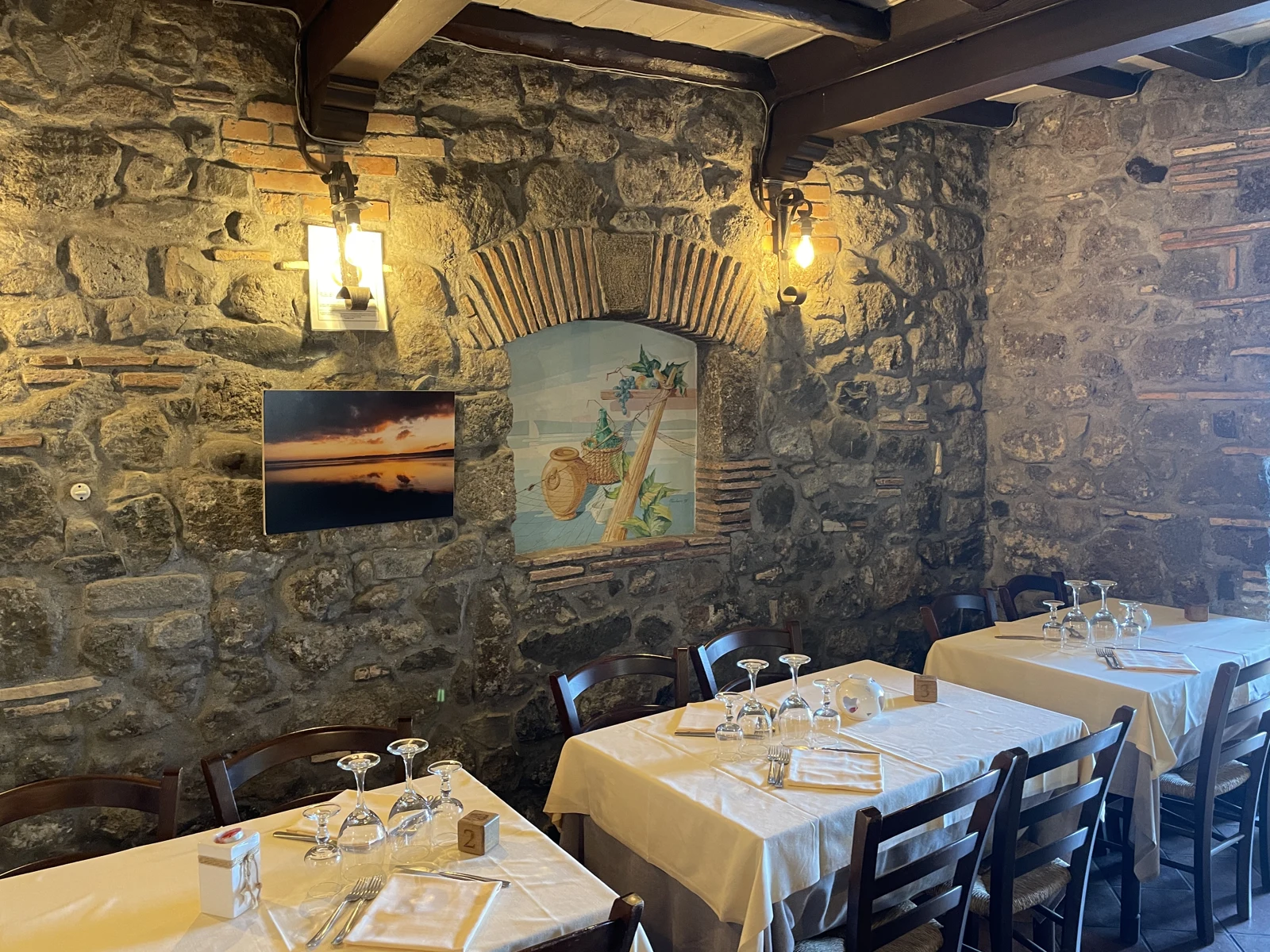 Le pareti in pietra e i tavoli apparecchiati della Tavernetta